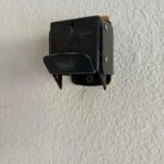 I saw this on the wall of the garage when I moved into this house. It appears to be a metal belt buckle, possibly serving as a stand.